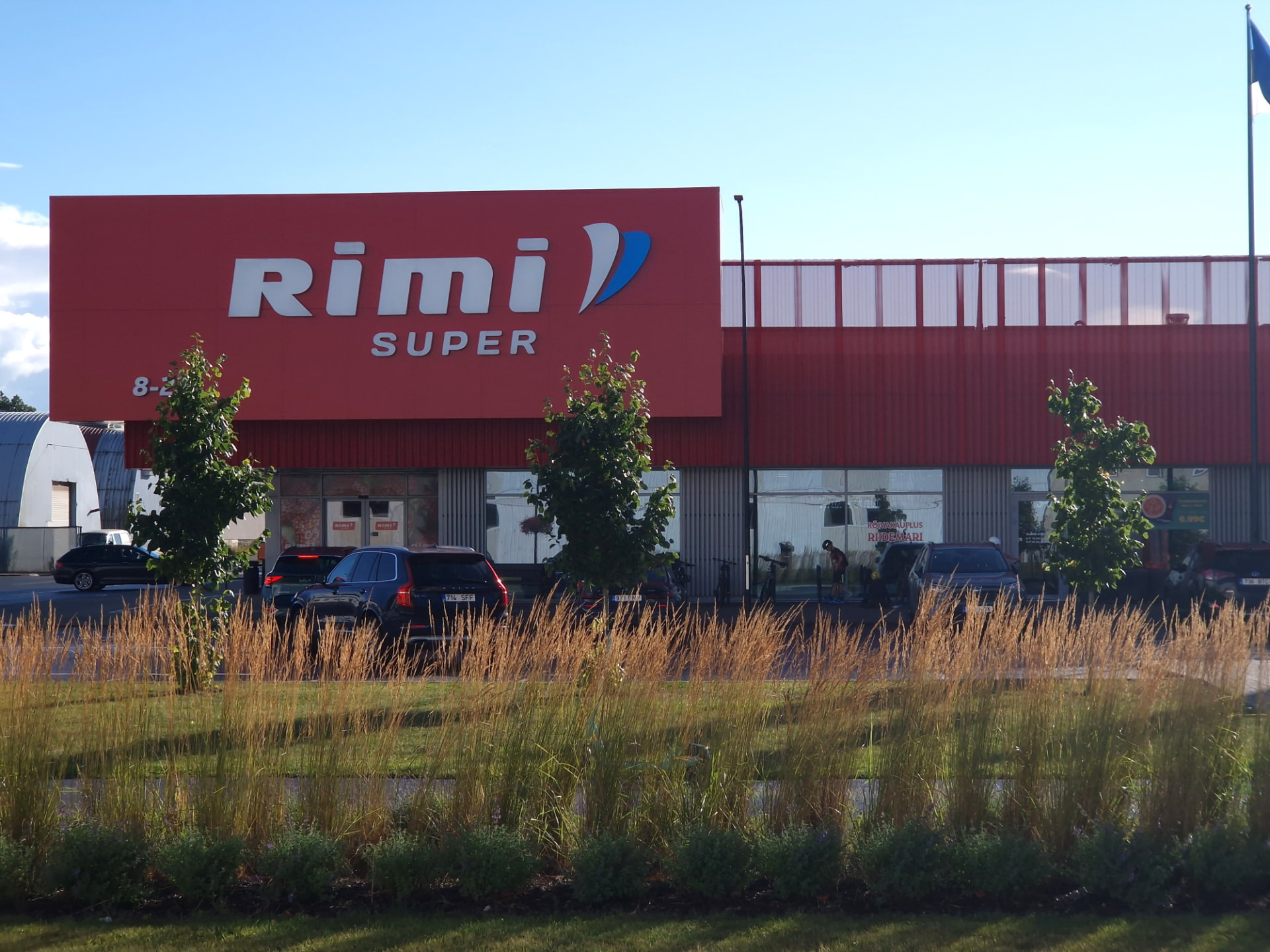 Saue Rimi — main facade with the Rimi Super sign seen across the meadow planting
