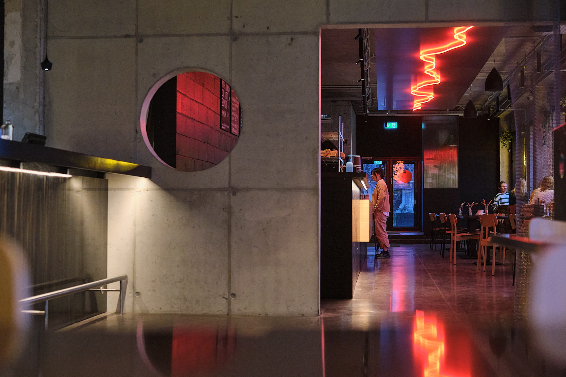 Restaurant Sumi, Tallinn — concrete wall with round opening and red neon in the dining hall beyond, photo by Kevin Loigu