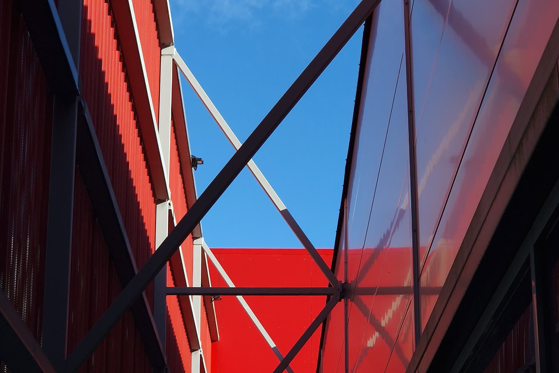 Saue Rimi — steel bracing and glazed canopy between the red facade planes
