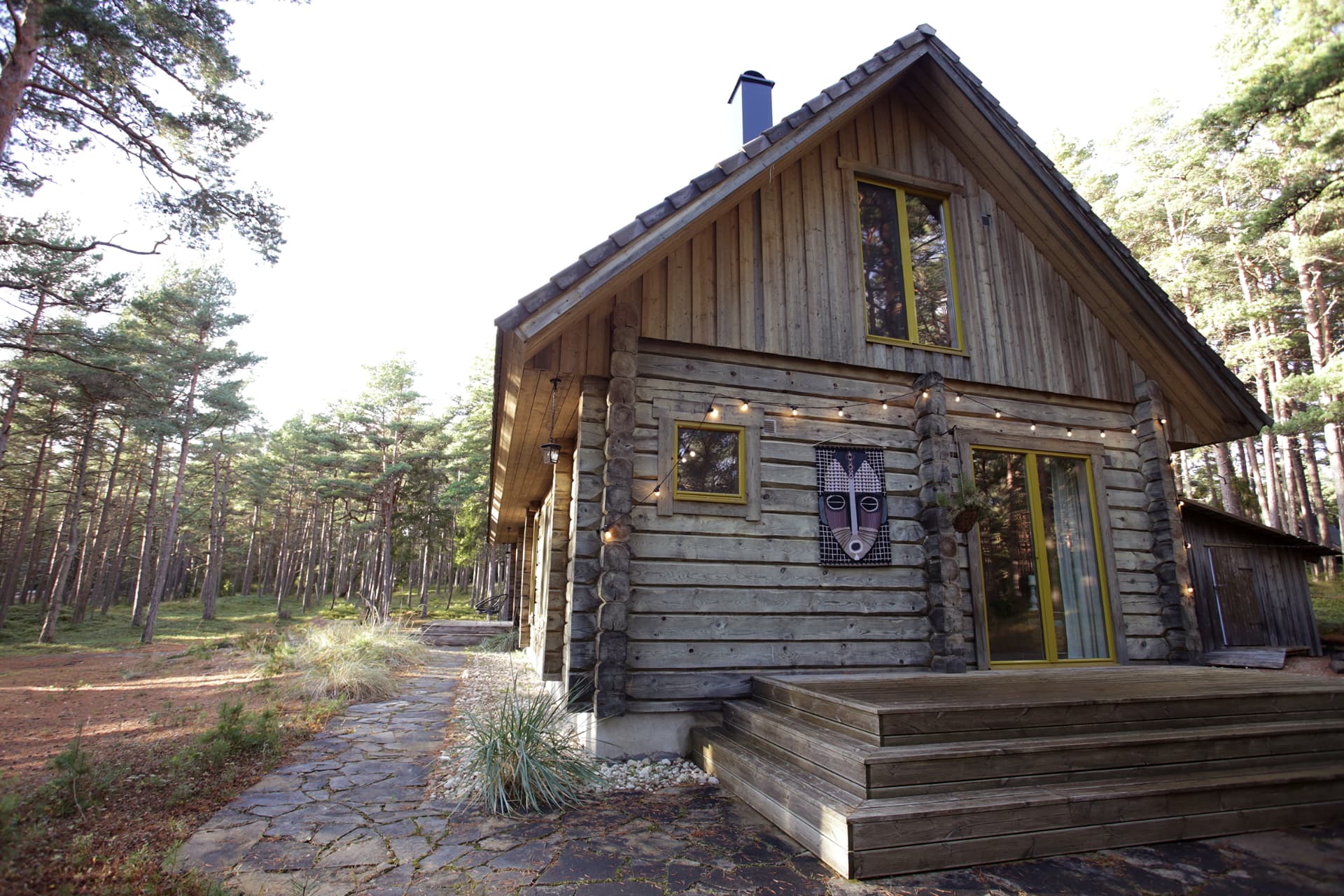Kalana House, Kalana — gable end and log walls among the pines, photo by Laura Nestor